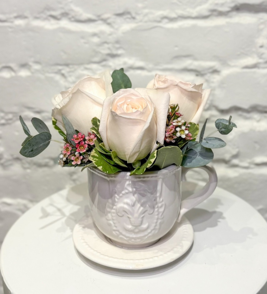Tea Time - Three beautiful garden roses accented with wax flower and greens, displayed in an adorable tea cup vase.
