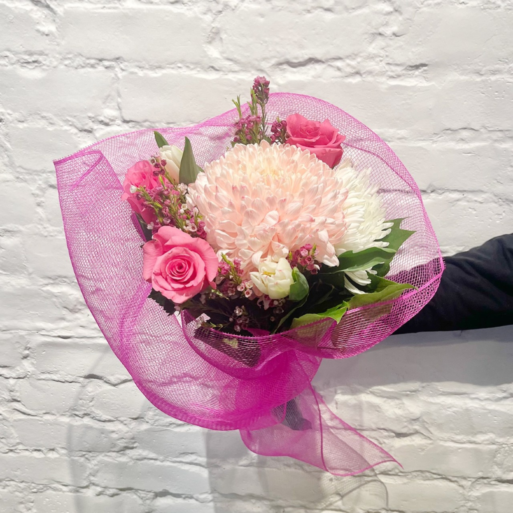 Bright pink roses, soft pink commercial mums, white fuji mums, tulips, wax flower, and salal expertly wrapped and hand tied.