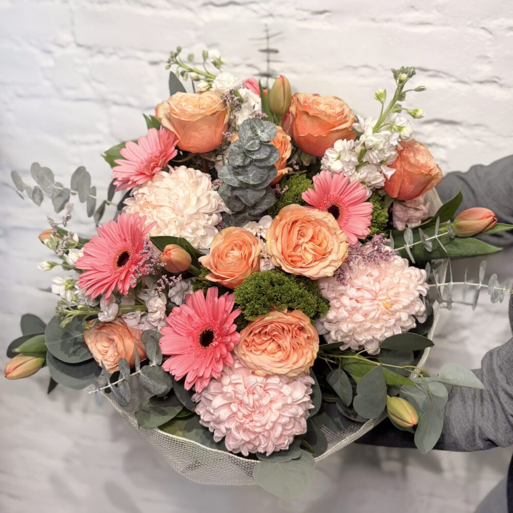 Mother’s Day hand-tied bouquet with roses, tulips, mini gerbera daisies and greenery wrapped