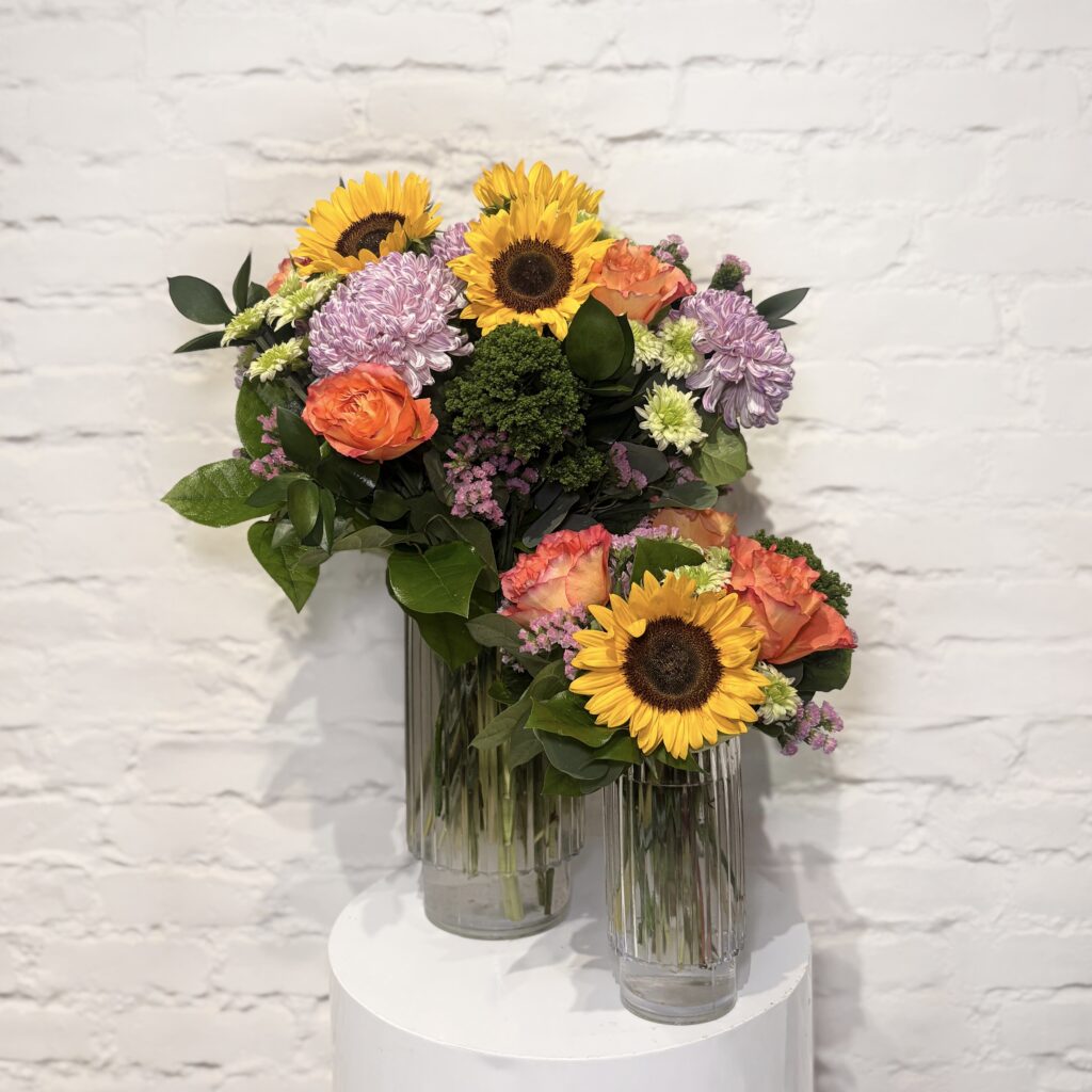 Sunflowers & Sunshine flower arrangement with sunflowers, roses, mums, poms, statice, trachelium and fresh greens